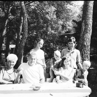 Family gathering outdoors at picnic table.