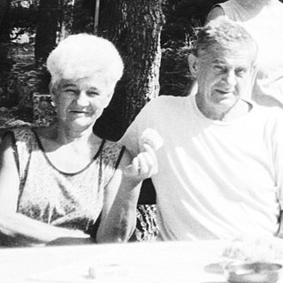 Family gathering outdoors at picnic table.
