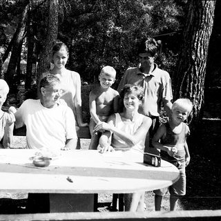 Family gathering outdoors by a picnic table.