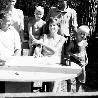 Family gathering outdoors by a picnic table.