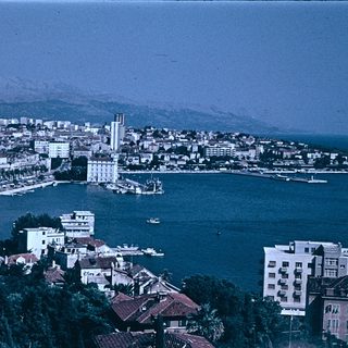 Coastal town with harbor, buildings, and sea.