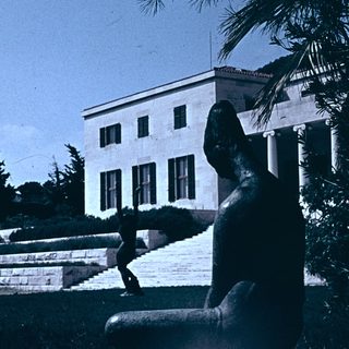 Neoclassical building with statue and steps.