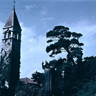 Historic church steeple with tall pine tree.
