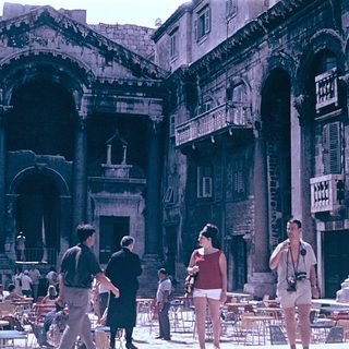 Historic Roman ruins with tourists in courtyard.