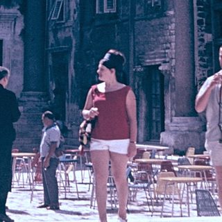Historic Roman ruins with tourists in courtyard.