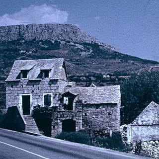 Rural stone houses beside mountainous terrain.