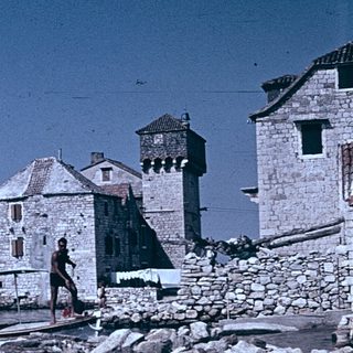 Historic stone buildings by waterfront with small boat.