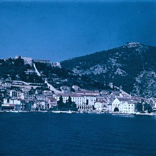 Coastal town nestled by lake with hillside buildings.