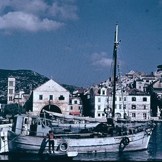 Coastal town harbor with traditional boats and historic buildings.