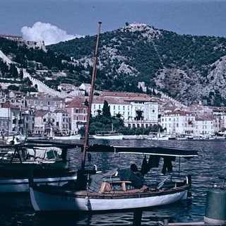 Coastal town with boats, historic buildings, and hills.
