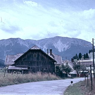 Rural mountain village with wooden barn and road.