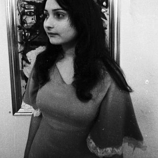 Woman posing beside abstract expressionist painting.