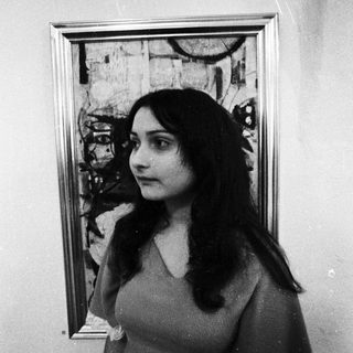 Woman posing beside abstract expressionist painting.