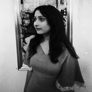 Woman posing beside abstract expressionist painting.