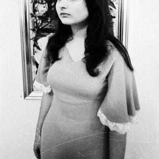 Woman posing in front of abstract artwork.