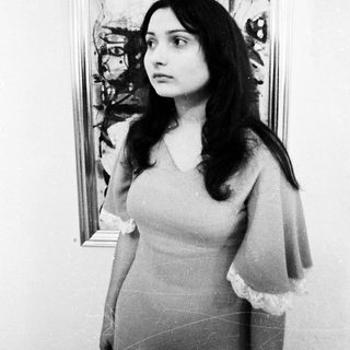 Woman posing in front of abstract artwork.