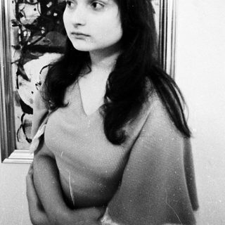 Young woman posing in front of abstract artwork.