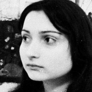 Young woman posing in front of abstract artwork.