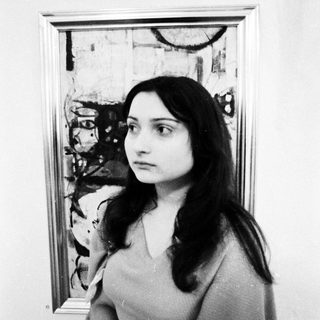 Young woman posing in front of abstract artwork.