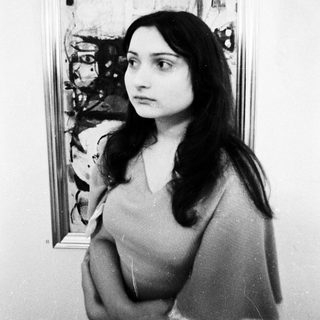 Young woman posing in front of abstract artwork.