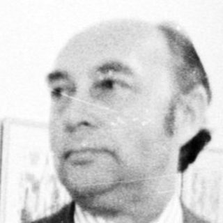 Man in suit standing beside abstract art exhibition.