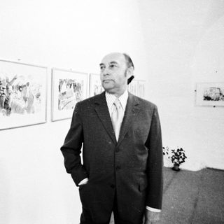 Man in suit standing beside abstract art exhibition.