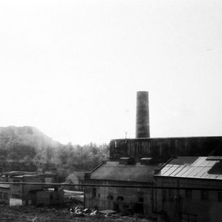 Industrial factory complex with tall smokestack.