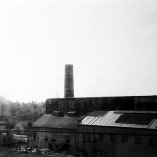 Industrial factory complex with tall smokestack.