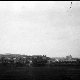 Industrial buildings by waterfront, hazy landscape.