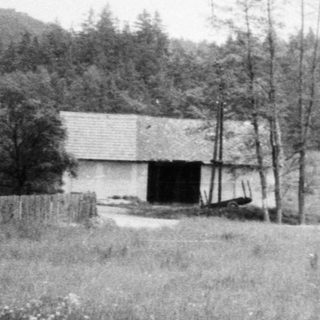 Rural landscape with old barn, open field, forest.