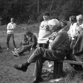Group of people gathered outdoors around a campfire.