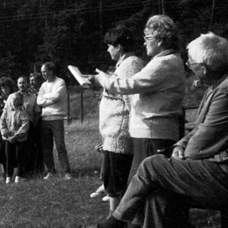 Group gathering outdoors listening to a speaker.