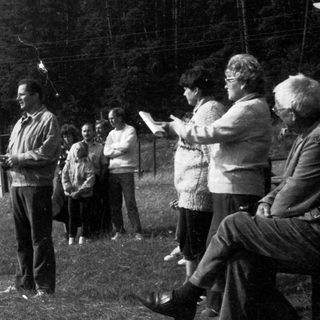 Group gathering outdoors listening to a speaker.
