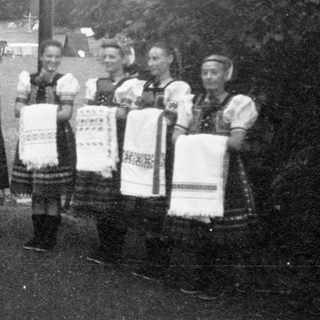 Traditional folk group in colorful embroidered costumes holding handkerchiefs.