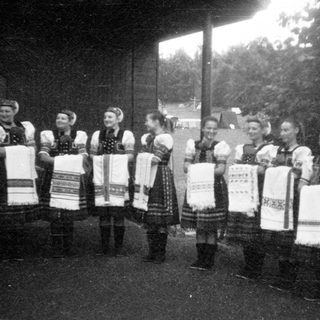 Traditional folk group in colorful embroidered costumes holding handkerchiefs.