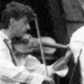 Three musicians playing traditional instruments outdoors near rustic buildings.