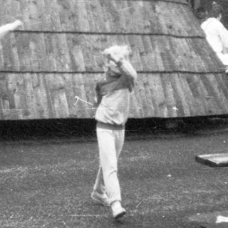 People playing frisbee outdoors near wooden structure.