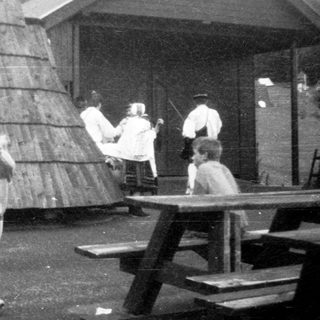 People playing frisbee outdoors near wooden structure.