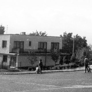 Suburban street corner with few pedestrians and residential buildings.