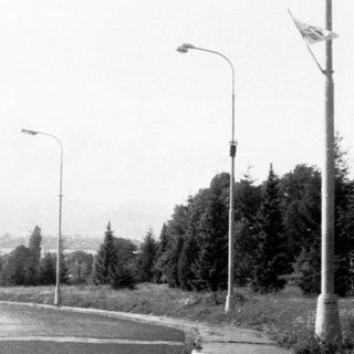 Suburban street corner with few pedestrians and residential buildings.