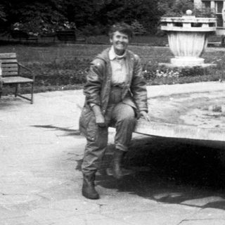 Man in 1960s-era flight suit posing near fountain.