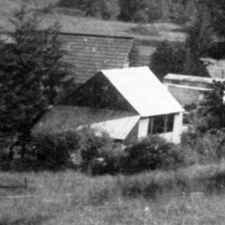 Rural countryside village with houses, trees, and hills.