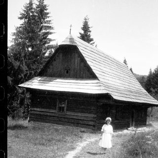 Traditional wooden church with woman standing outside.