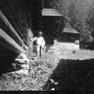 Rural scene with person standing near rustic stone house.
