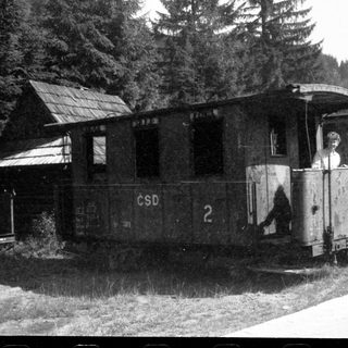 Vintage ČSD narrow-gauge train car near wooden station.