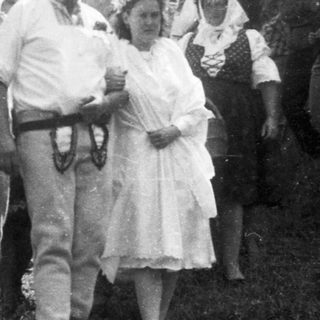 Group of people gathered outdoors in rural setting, mid-20th century.