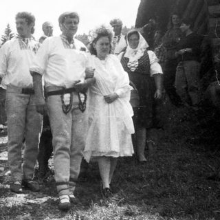 Group of people gathered outdoors in rural setting, mid-20th century.