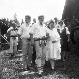 Group of people gathered outdoors in rural setting, mid-20th century.
