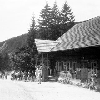 Vintage mountain village scene with horse-drawn carts and crowd.