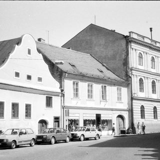 Historic European street with classic buildings and parked cars.